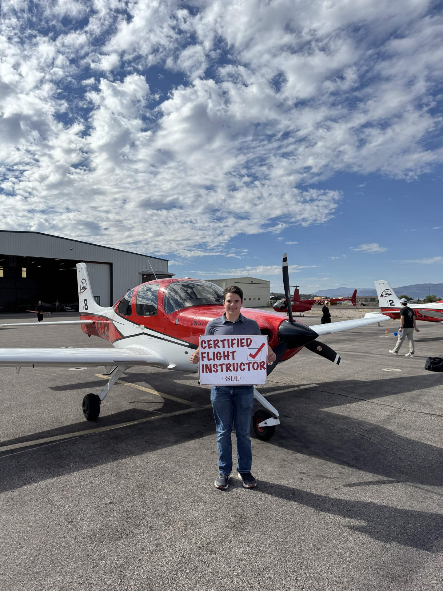 Shawn Pena, Certified Flight Instructor in Cedar City, Utah, holding his CFI certificate sign in front of a training airplane